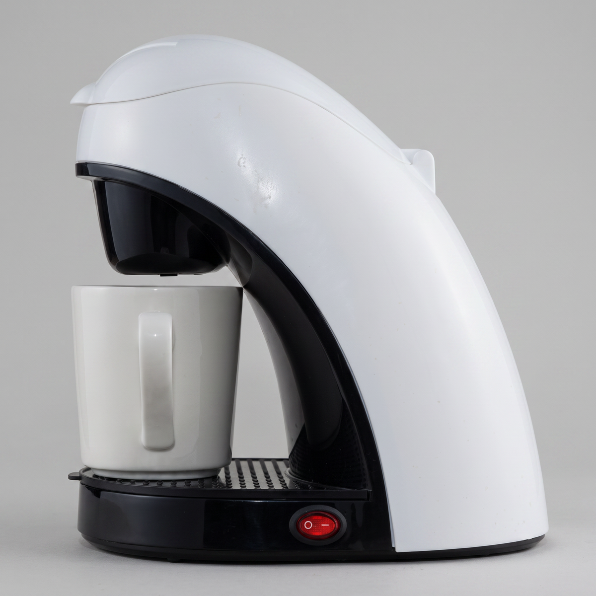 White single-serve coffee maker with mug on a clean white studio background, product catalog photo