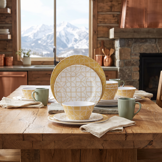Laurie Gates California Designs Summer Bloom 12-piece melamine dinnerware set in gold, staged in a mountain cabin dining setting with a snow-capped mountain view